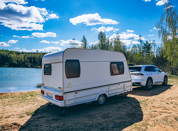 camper being pulled by a truck next to a lake