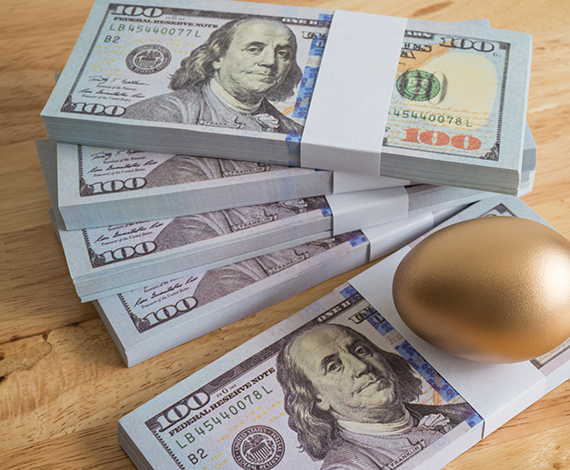 a golden egg sitting on stacks of one hundred dollar bills