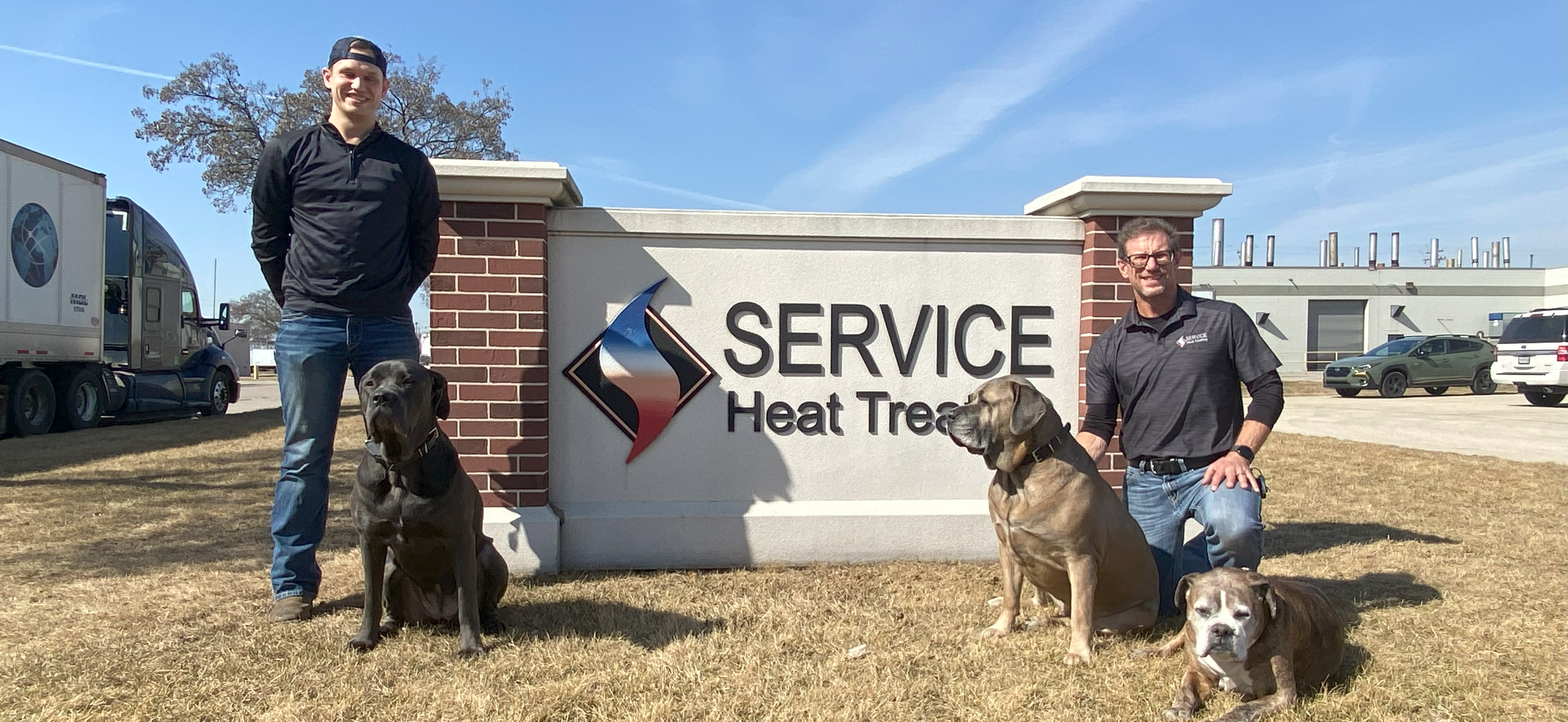 BCT team members standing next to the monument sign with their dogs